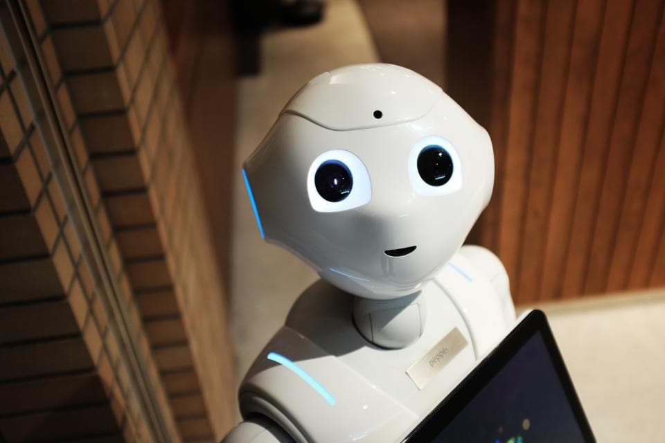 Service robot working at a laptop, standing in for AI-assisted support