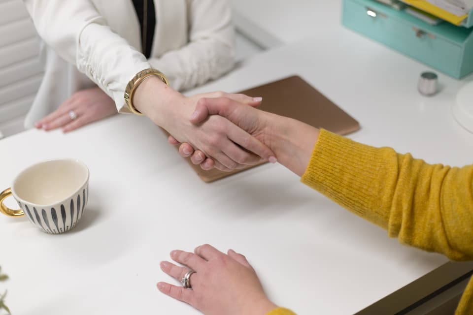 An adviser and client shaking hands over a policy review